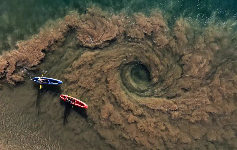 Canoes over sand swirls in the estuary