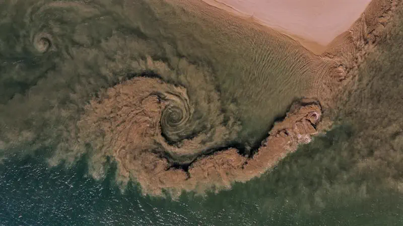 Sand swirls in the river